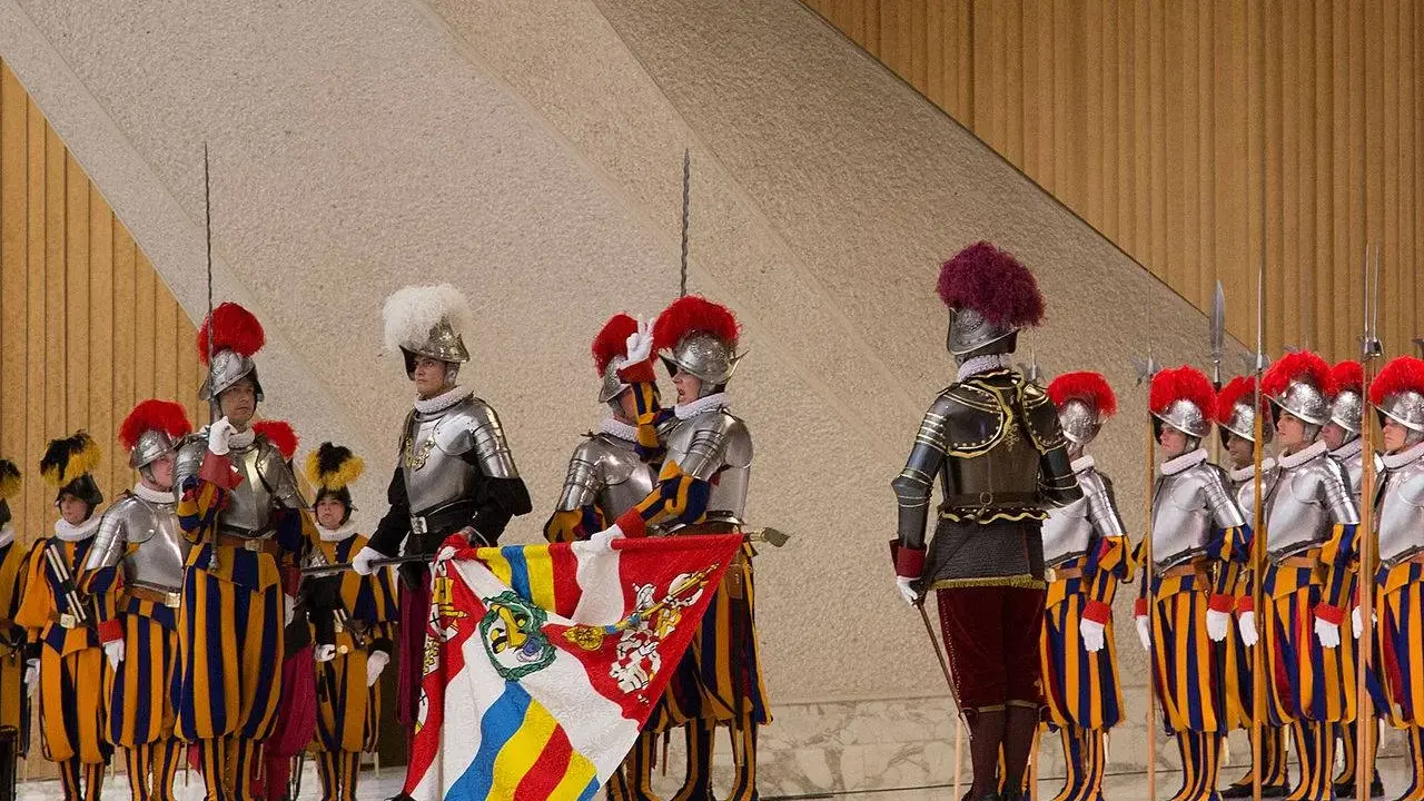 Guardie svizzere in alta uniforme, con alabarde e stendardo. Forse il loro celibato spiega perché le guardie svizzere non si possono sposare.