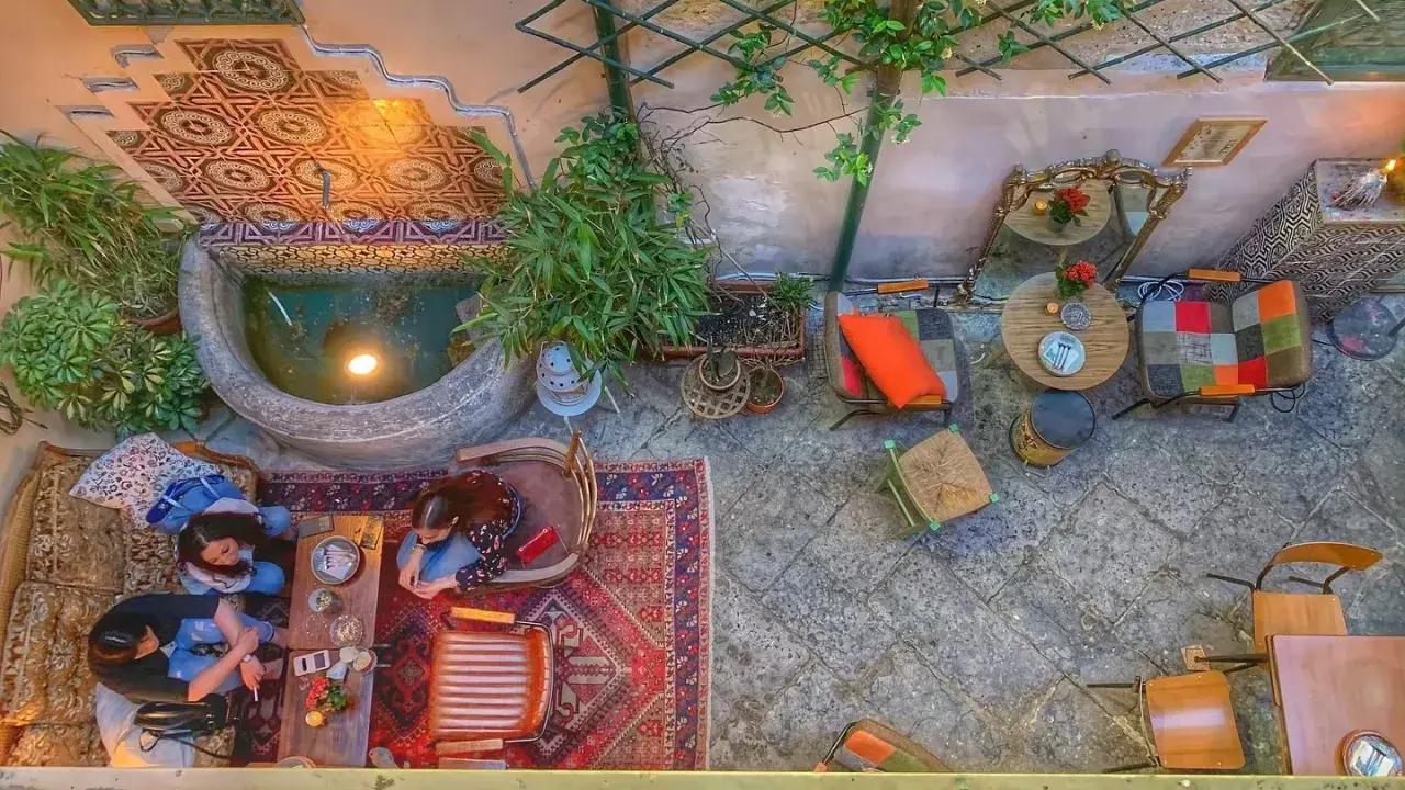 Cortile interno con fontana, piante e arredi colorati. Un luogo ideale a Palermo dove si mangia e si balla, tra tappeti e luci soffuse.