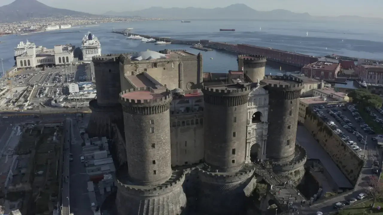 Maschio Angioino con la Cappella Palatina, imponente castello medievale a Napoli, affacciato sul mare con il Vesuvio sullo sfondo.