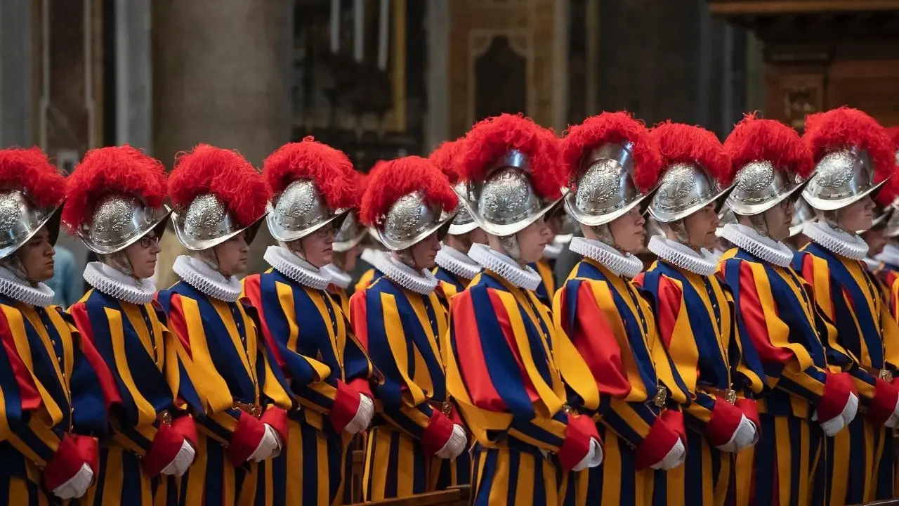 Guardie svizzere in divisa colorata, con elmi piumati, spiegano perchè il Papa ha le guardie svizzere: sono la sua protezione storica.