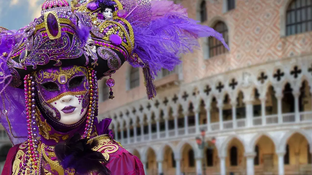 Un elaborato costume di Carnevale a Venezia, uno dei carnevali famosi in Italia, con maschera viola e oro, piume e perline.