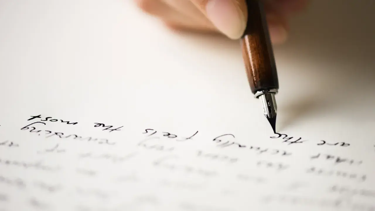 Mano che scrive con una penna stilografica su carta, evocando il significato di un rapporto epistolare.