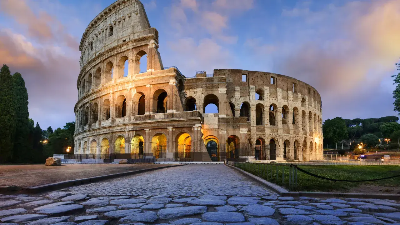 Il Colosseo, uno dei monumenti famosi a Roma, illuminato al tramonto con un cielo nuvoloso.