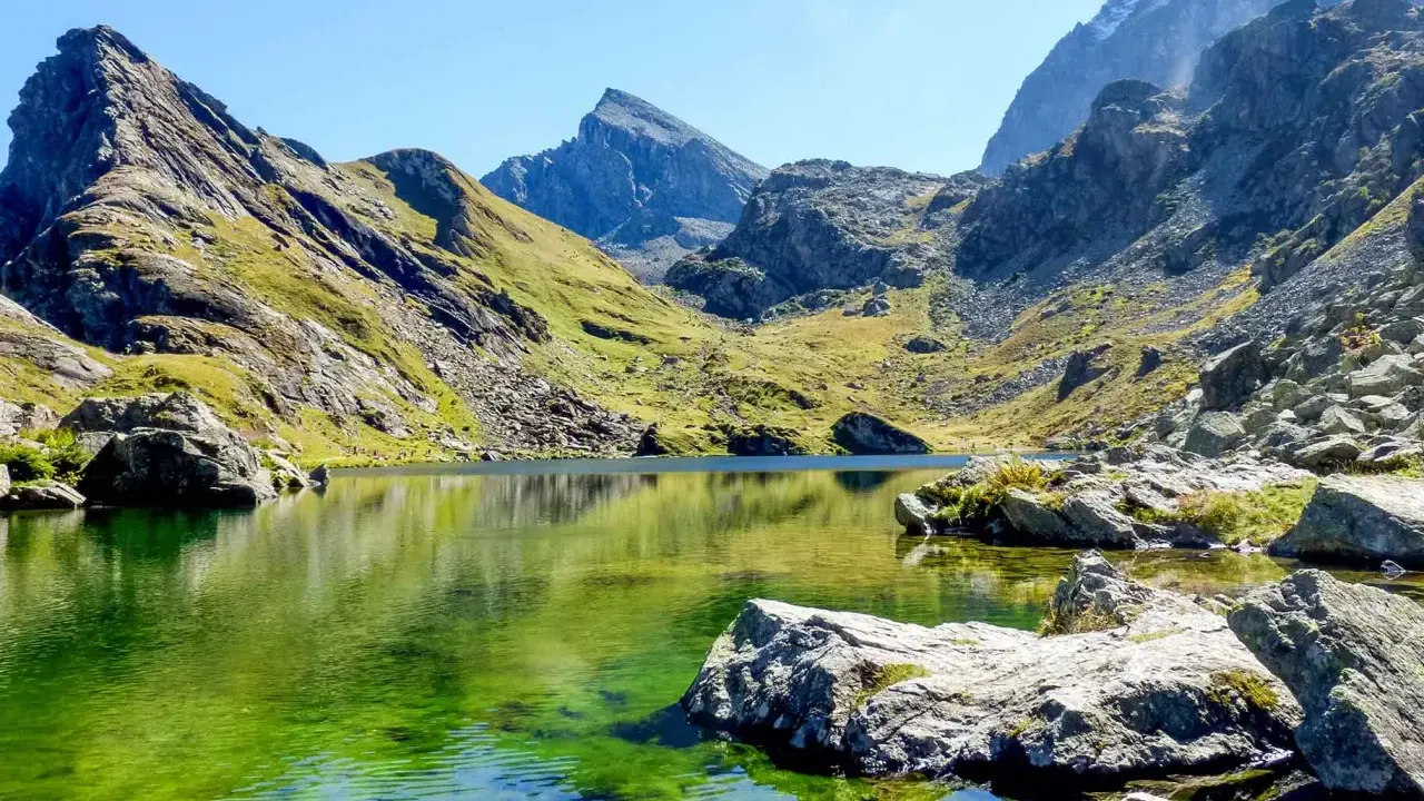 Lago alpino dalle acque smeraldine, incastonato tra montagne scoscese e verdi pendii. Un angolo di pace nell'Italia del Nord.