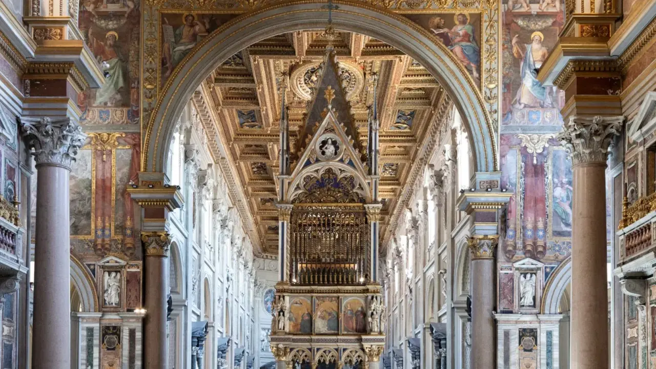 Interno di San Giovanni in Laterano: maestoso baldacchino, affreschi dorati e colonne imponenti creano un'atmosfera sacra.