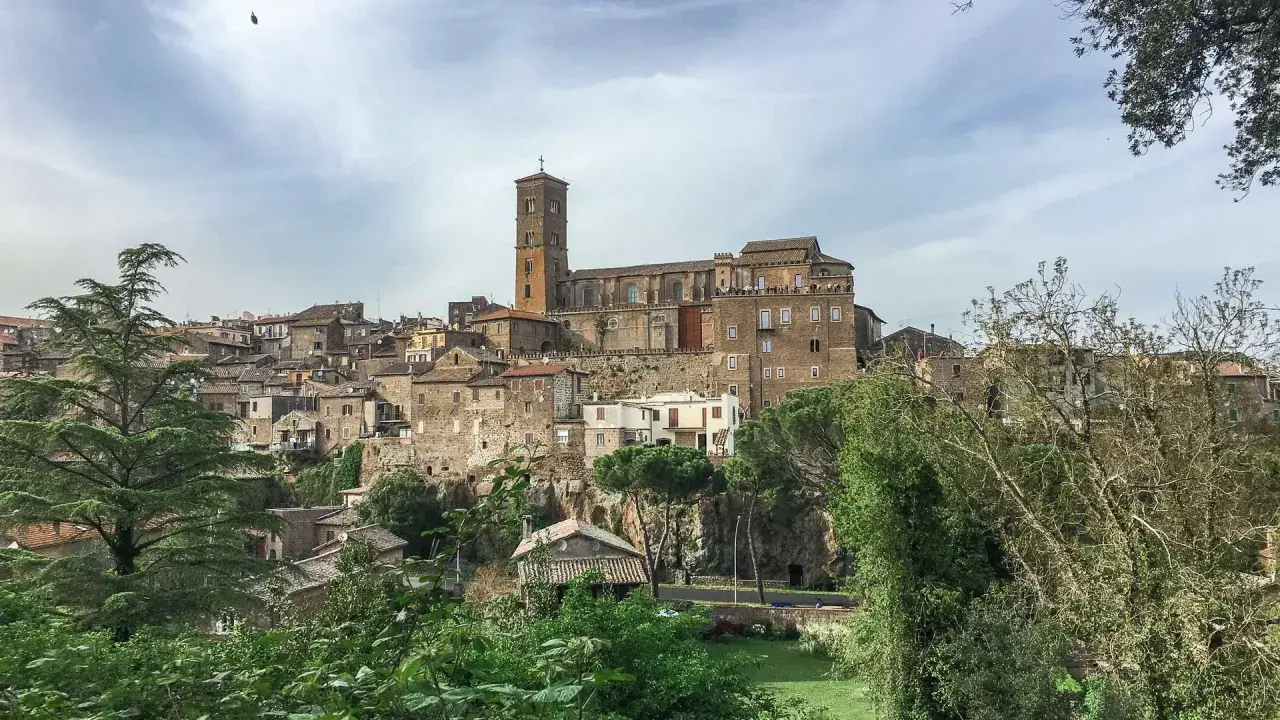 Panoramica dell'antico borgo di Sutri, con le sue case in pietra arroccate su una collina e una maestosa cattedrale con campanile.