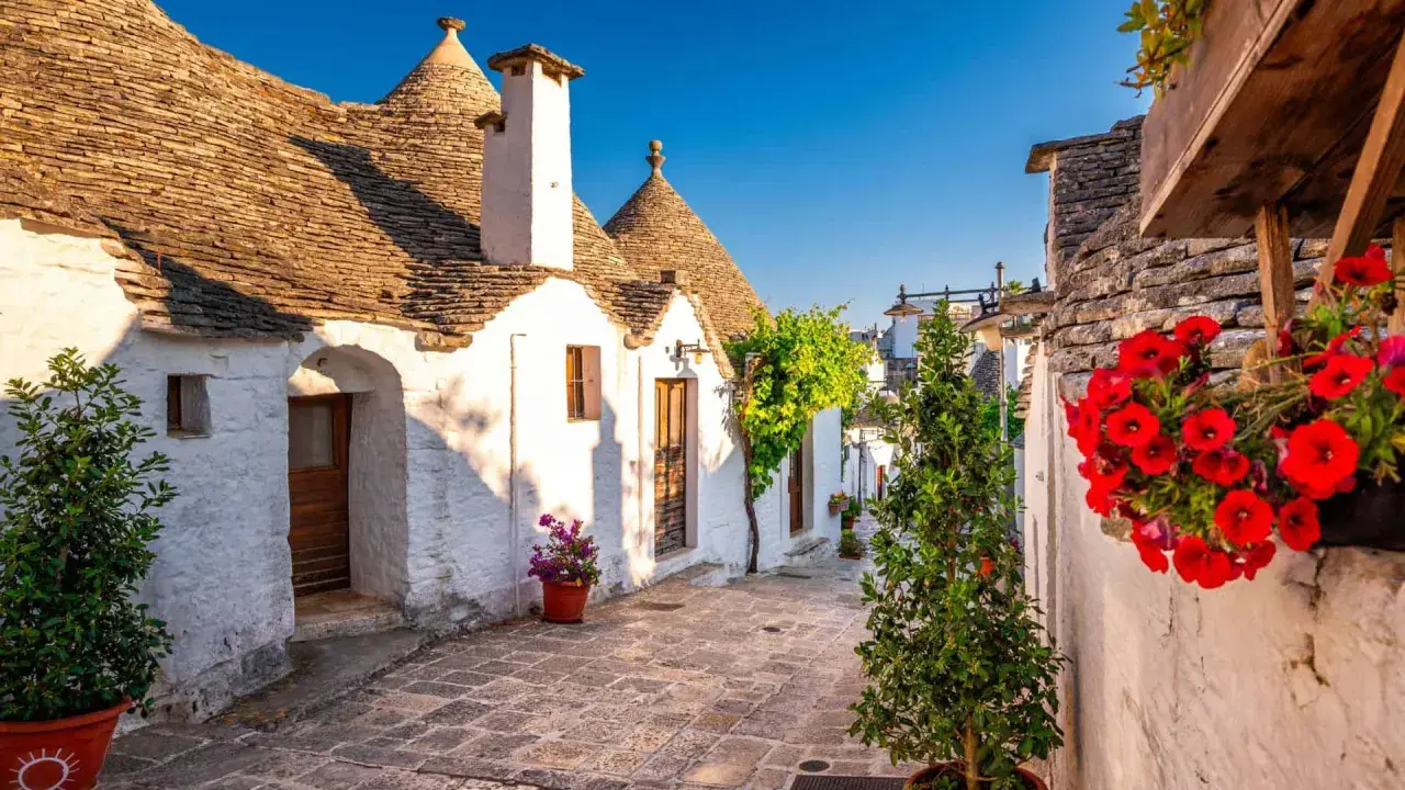 Un vicolo fiorito tra i trulli di Alberobello, un'idea perfetta per sapere dove andare in primavera.