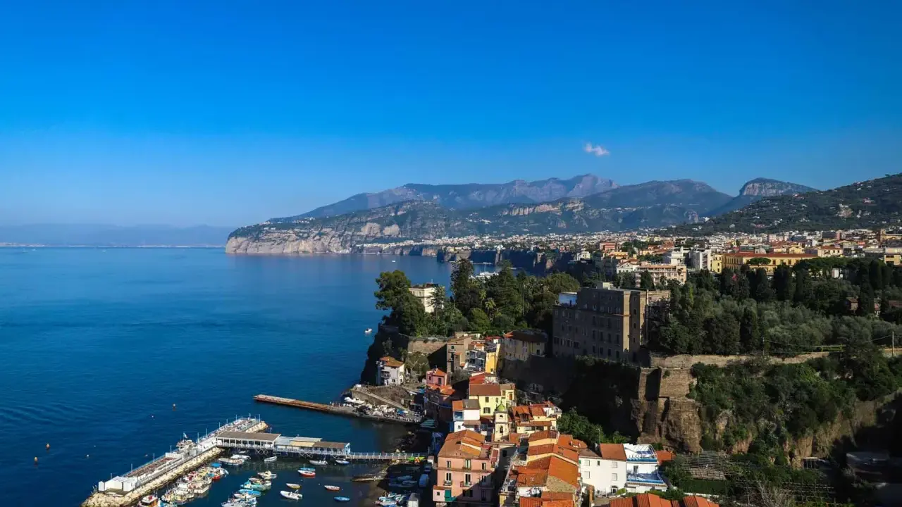 Vista panoramica di Sorrento: cosa vedere a Sorrento in un giorno, con il porto, le case colorate a picco sul mare e i monti sullo sfondo.