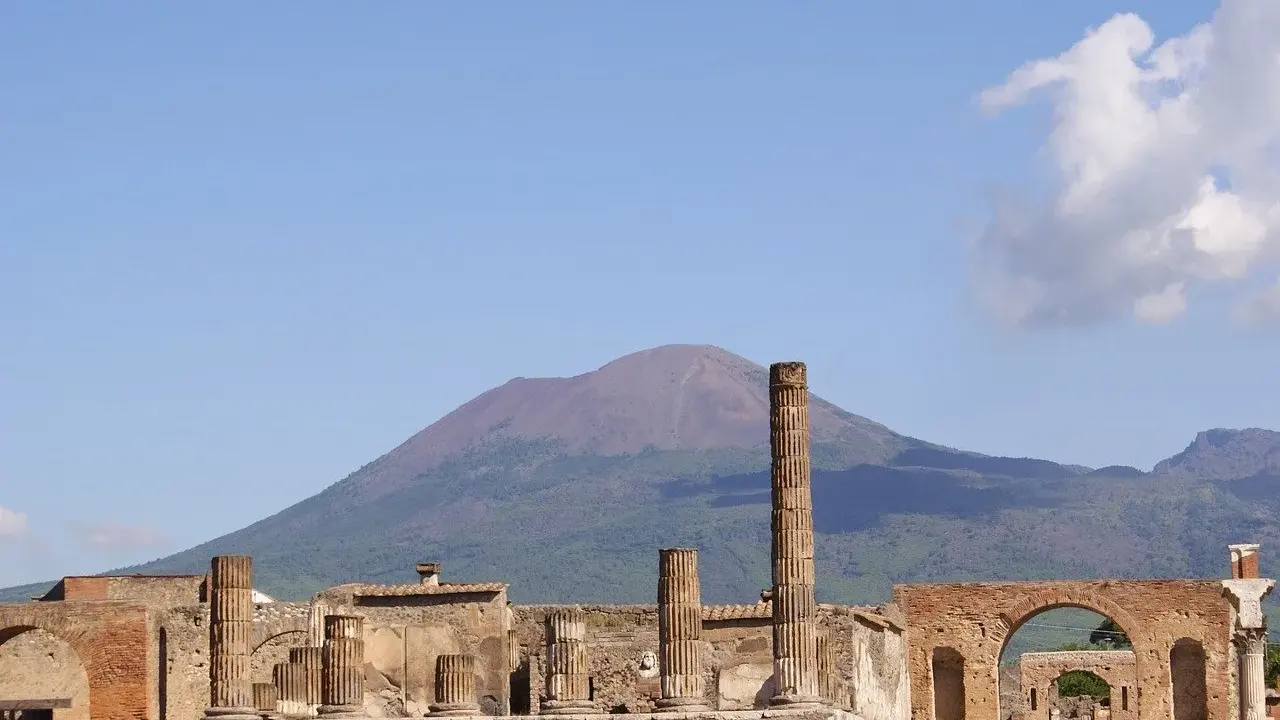 Rovine di Pompei con il Vesuvio sullo sfondo. Un'idea per cosa visitare a Pompei in un giorno, tra colonne antiche e storia millenaria.