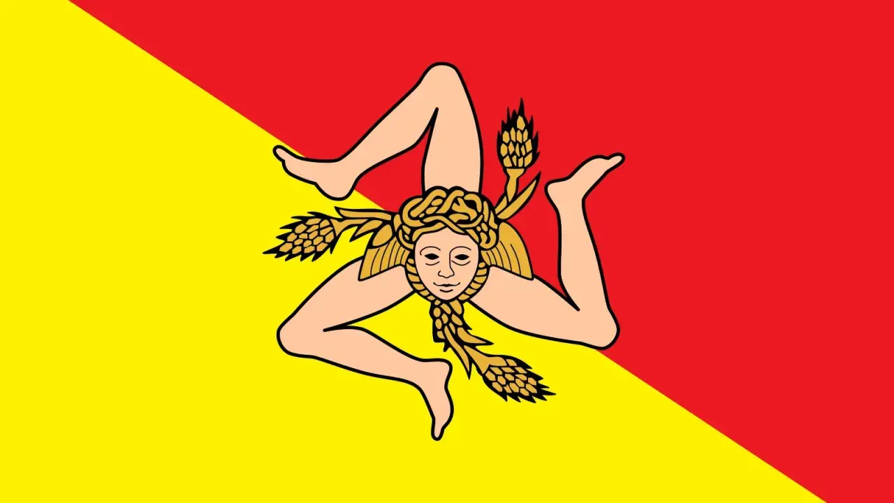 Lo stemma della Sicilia, la Trinacria, con la testa di Medusa e tre spighe di grano, su sfondo diviso in giallo e rosso.