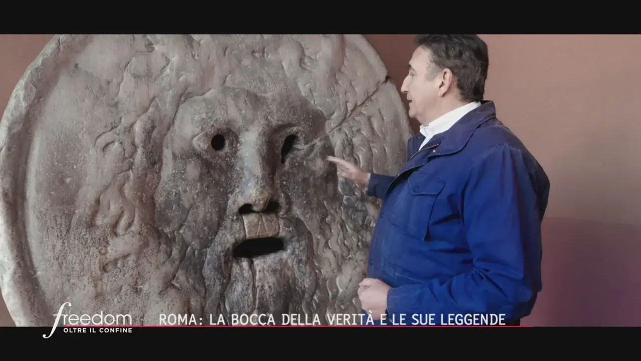 Un uomo indica la Bocca della Verità a Roma, un'antica scultura che si dice morda la mano dei bugiardi. Il suo significato è legato alla giustizia e alla verità.