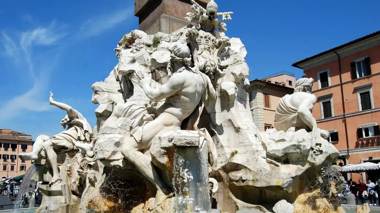 Fontana dei Quattro Fiumi di Bernini in Piazza Navona, Roma. Sculture maestose e acqua zampillante sotto un cielo azzurro.