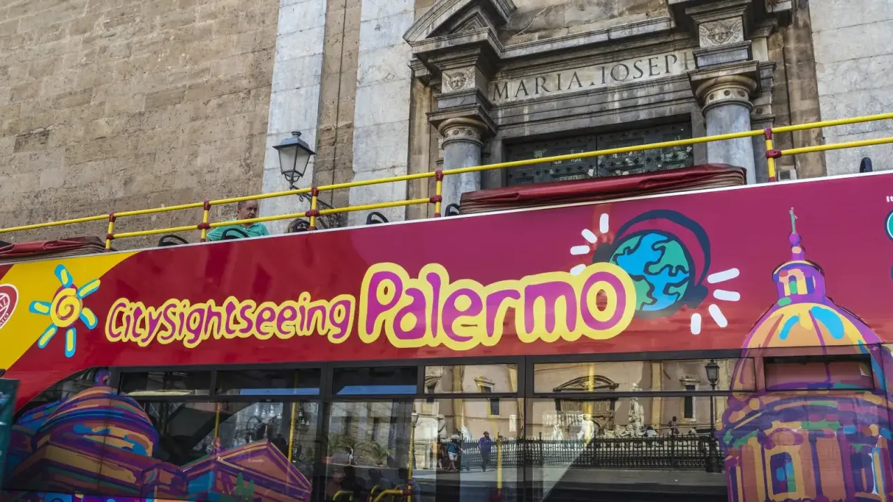 Autobus turistico rosso con scritta "City sightseeing Palermo". Un modo comodo per muoversi a Palermo e ammirare i monumenti.