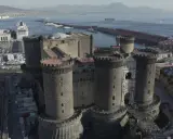 Maschio Angioino con la Cappella Palatina, imponente castello medievale a Napoli, affacciato sul mare con il Vesuvio sullo sfondo.