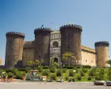 Il maestoso Maschio Angioino di Napoli, con le sue torri imponenti e l'arco trionfale, si staglia contro il cielo azzurro.