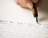 Mano che scrive con una penna stilografica su carta, evocando il significato di un rapporto epistolare.
