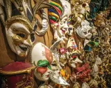 Una parete piena di maschere di carnevale romane, riccamente decorate, pronte per un ballo in maschera.