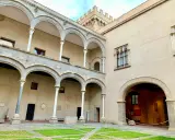 Cortile di Palazzo Abatellis, con arcate sovrapposte, finestre gotiche e opere d'arte esposte.