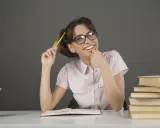 Ragazza con occhiali e matita gialla, un libro aperto e pile di libri, un'espressione pensierosa che ricorda l'anastrofe figura retorica.