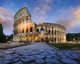 Il Colosseo, uno dei monumenti famosi a Roma, illuminato al tramonto con un cielo nuvoloso.