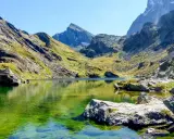 Lago alpino dalle acque smeraldine, incastonato tra montagne scoscese e verdi pendii. Un angolo di pace nell'Italia del Nord.
