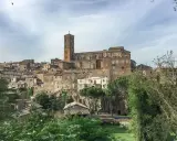 Panoramica dell'antico borgo di Sutri, con le sue case in pietra arroccate su una collina e una maestosa cattedrale con campanile.