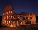 Il Colosseo illuminato di notte, con i suoi archi che creano un gioco di luci e ombre. Ci si chiede perche il Colosseo è bucato, ma la sua storia è scritta nelle sue ferite.