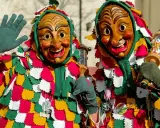 Due maschere di carnevale in Italia, con costumi colorati e volti grotteschi, salutano festanti.