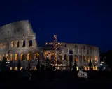 Colosseo illuminato di notte con una croce luminosa, un'atmosfera suggestiva che ricorda quando si festeggia Pasqua.