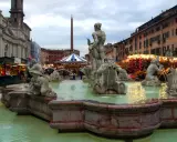 Fontana dei Quattro Fiumi a Piazza Navona, Roma, con bancarelle illuminate che anticipano quando iniziano i mercatini di Natale a Roma.
