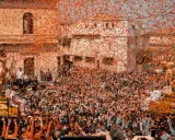 Folla festante sotto una pioggia di coriandoli arancioni, mentre si celebra cosa si festeggia a Pasqua con una processione solenne.