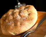 Focaccia rustica con sale grosso e rosmarino, pronta per essere tagliata. Un invito a gustare, come il pan per focaccia significato.