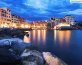 Case colorate illuminate sul mare calmo, la **riviera ligure di levante** incanta al crepuscolo.