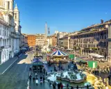 Piazza Navona a Roma a dicembre, con giostra, fontana e bancarelle.