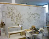 Bozzetto del "Trionfo di Bacco e Arianna" su un muro, con schizzi di figure e strumenti da pittura sparsi.