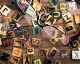 Un occhio attento scruta le lettere sparse, una figura retorica che unisce due termini contraddittori, creando un caos ordinato di parole.