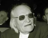 Un uomo anziano con occhiali da sole, capelli lunghi e bianchi, sembra un poeta. Sono una creatura ungaretti.