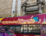 Autobus turistico rosso con scritta "City sightseeing Palermo". Un modo comodo per muoversi a Palermo e ammirare i monumenti.