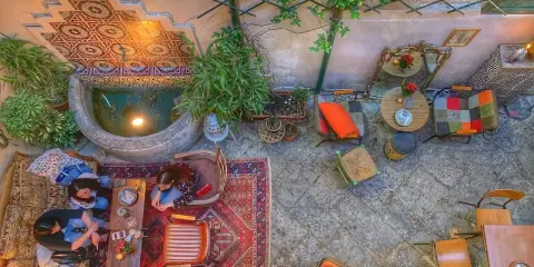 Cortile interno con fontana, piante e arredi colorati. Un luogo ideale a Palermo dove si mangia e si balla, tra tappeti e luci soffuse.