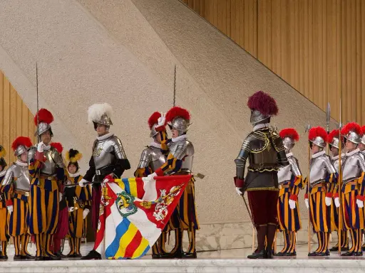 Guardie svizzere in alta uniforme, con alabarde e stendardo. Forse il loro celibato spiega perché le guardie svizzere non si possono sposare.