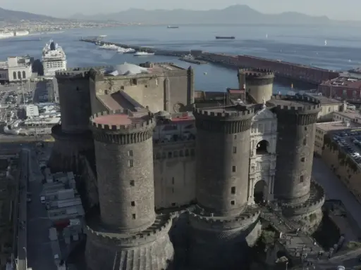 Maschio Angioino con la Cappella Palatina, imponente castello medievale a Napoli, affacciato sul mare con il Vesuvio sullo sfondo.
