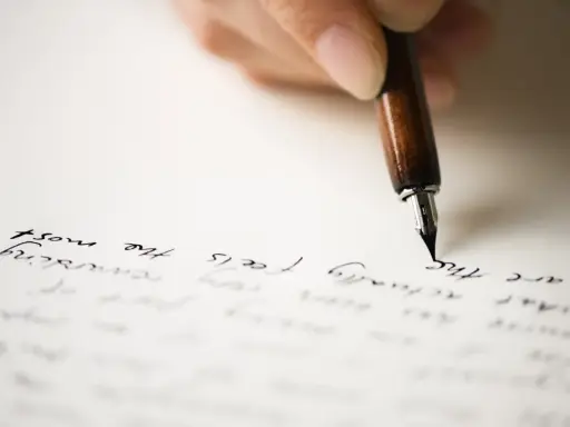 Mano che scrive con una penna stilografica su carta, evocando il significato di un rapporto epistolare.
