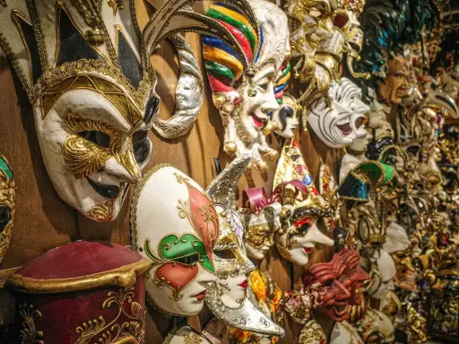 Una parete piena di maschere di carnevale romane, riccamente decorate, pronte per un ballo in maschera.