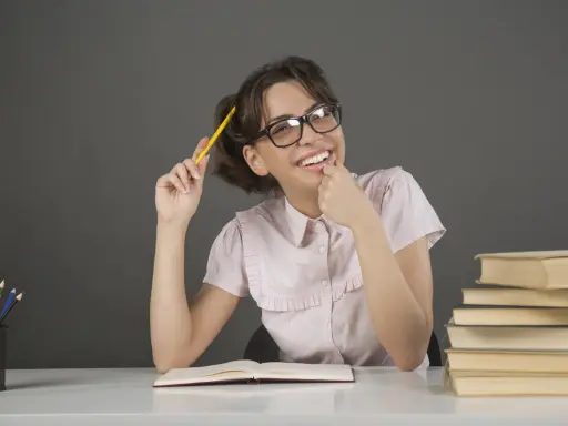 Ragazza con occhiali e matita gialla, un libro aperto e pile di libri, un'espressione pensierosa che ricorda l'anastrofe figura retorica.