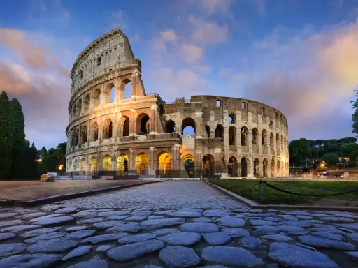 Il Colosseo, uno dei monumenti famosi a Roma, illuminato al tramonto con un cielo nuvoloso.
