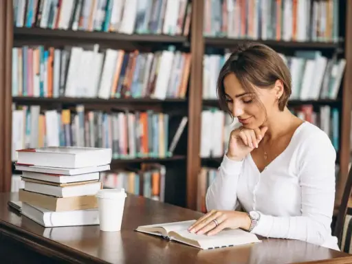 Donna legge in biblioteca, circondata da libri. Il suo studio è un esempio di come l'asindeto, nel significato e negli esempi, arricchisca la narrazione.