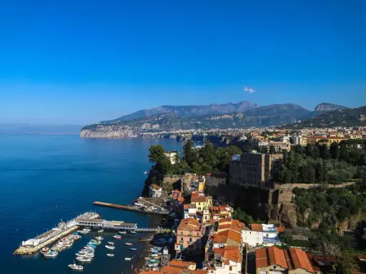 Vista panoramica di Sorrento: cosa vedere a Sorrento in un giorno, con il porto, le case colorate a picco sul mare e i monti sullo sfondo.