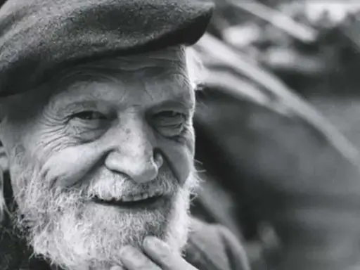 Un anziano con barba e berretto, il suo sorriso saggio evoca il significato che la morte si sconta vivendo appieno ogni istante.