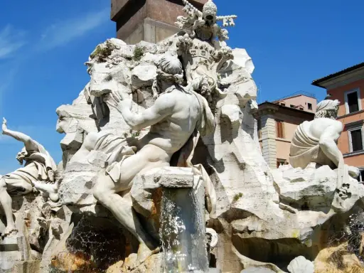 Fontana dei Quattro Fiumi di Bernini in Piazza Navona, Roma. Sculture maestose e acqua zampillante sotto un cielo azzurro.