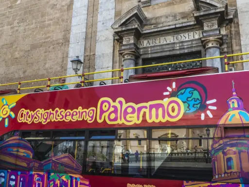Autobus turistico rosso con scritta "City sightseeing Palermo". Un modo comodo per muoversi a Palermo e ammirare i monumenti.